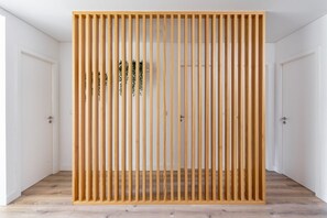 Une pièce avec une cloison en lattes de bois, des portes blanches et un plancher en bois.