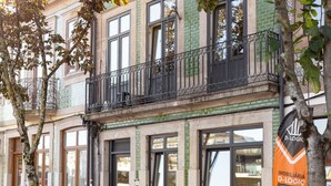 A building with a balcony, large windows, and a sign for 'D-LOGIC IMOBILIÁRIA'.