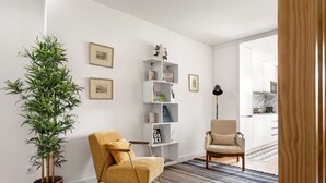 A modern living room with a yellow armchair, a bookshelf, and a large potted plant.