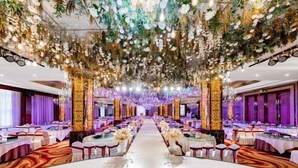 Un salón de banquetes con una larga mesa, sillas y decoración floral.