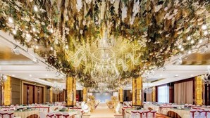 Un salón de banquetes con un pasillo central, mesas redondas y una araña.