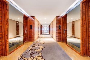 A hotel corridor with wooden paneling, a patterned carpet, and mirrored walls. - Triumphal Gate Holiday Hotel (Toketo No.1 Middle School) (Togtoh County)