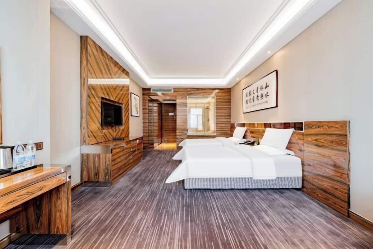 A hotel room with a wooden accent wall, a bed, a desk, and a mirror.