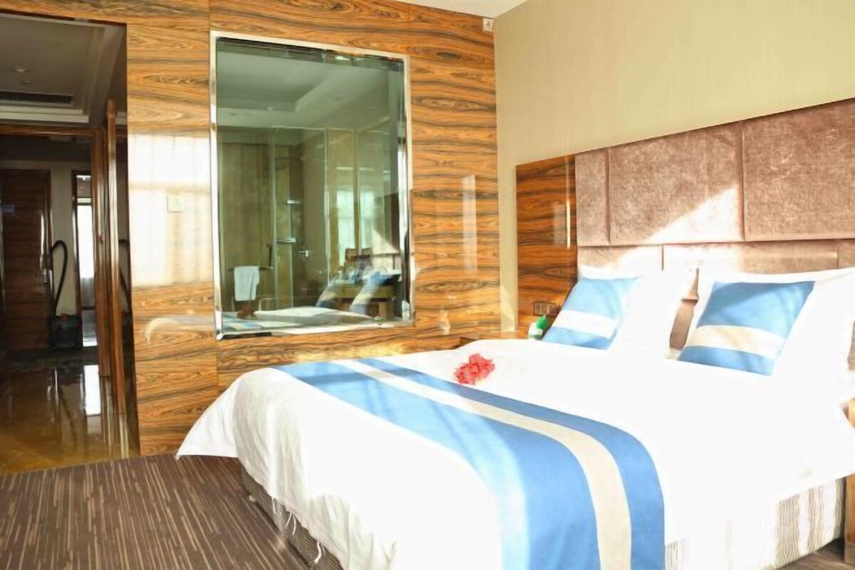 Ein Hotelzimmer mit einem großen Bett, Holzvertäfelung, einem großen Spiegel und Blick ins Badezimmer.