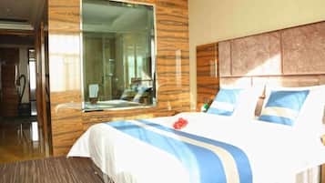 Habitación de hotel con una cama grande, paneles de madera, un espejo amplio y vista al baño.