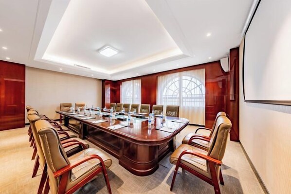 A conference room with a large oval table, leather chairs, and a projector screen.