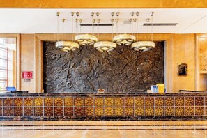 A reception area with a decorative wall, a reception desk, and a tiled floor. - Triumphal Gate Holiday Hotel (Toketo No.1 Middle School) (Togtoh County)