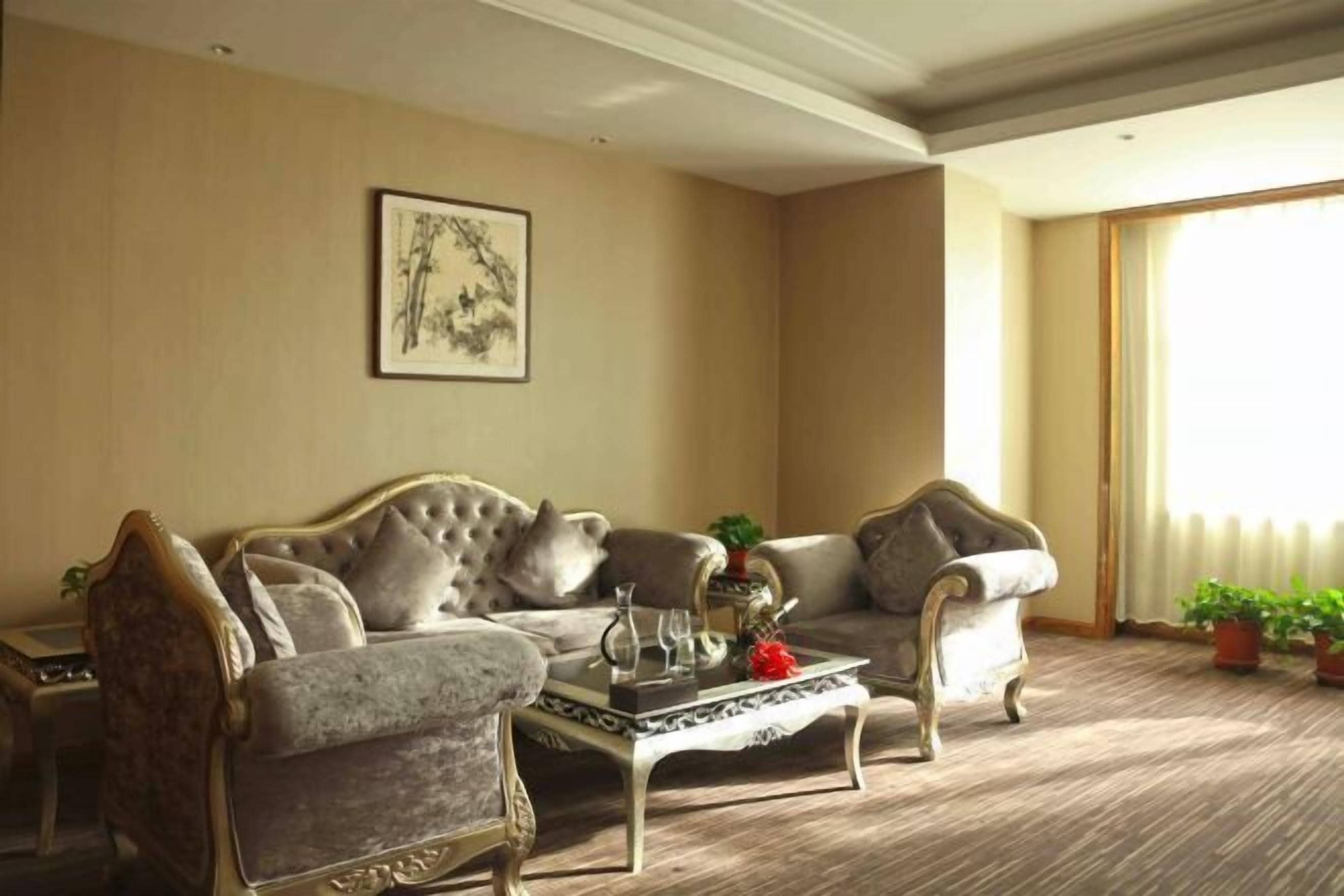 Una sala de estar con sofá, sillones, una mesa de centro y un cuadro en la pared.