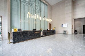 A hotel reception area with a marble counter, modern pendant lighting, and a large glass wall. - Yeste International Hotel （Chengdu Shuangliu Airport Wanda Plaza Branch)） (Chengdu)