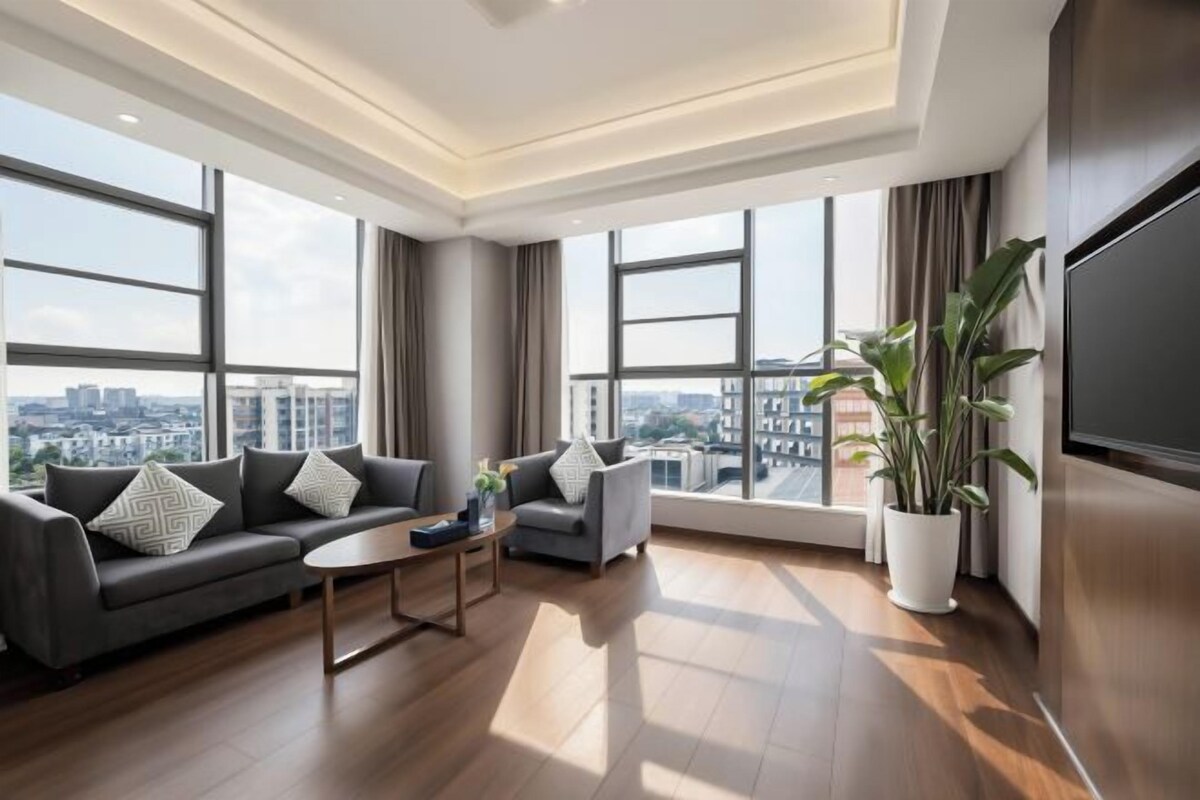 Een moderne woonkamer met een bank, fauteuil, salontafel en potplanten.