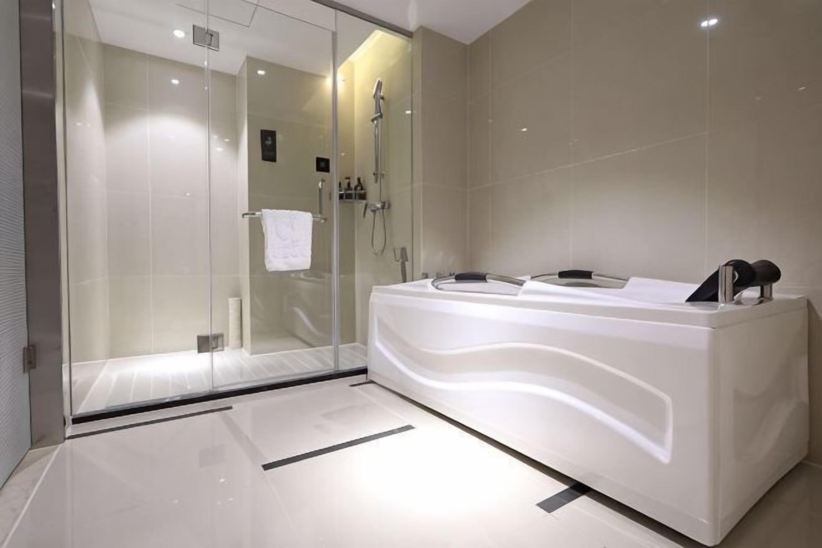 A modern bathroom with a glass-enclosed shower, a large white bathtub, and a sleek vanity.