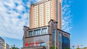 Un moderno edificio de hotel con un llamativo letrero rojo y un amplio frente de cristal.