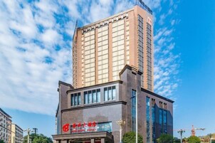 Un moderno edificio de hotel con un llamativo letrero rojo y un amplio frente de cristal.