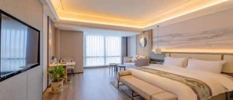 Una habitación de hotel moderna con una cama grande, un escritorio, una silla y un televisor.
