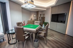 Quarto com mesa de bilhar, cadeiras, televisão e cozinha compacta.