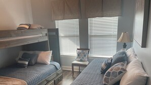 A bedroom with a bunk bed, a single bed, and a chair. There are two windows with blinds, a lamp, and a framed picture on the wall. - Angler Sunrise..Luxury House on water (Hackberry)