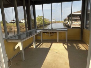 A small, enclosed outdoor space with a window overlooking a body of water and a distant building.