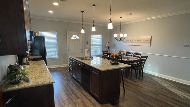 A modern kitchen with dark wood cabinets, a central island, and pendant lighting. - Angler Sunrise..Luxury House on water (Hackberry)