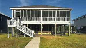 A two-story house with a covered porch, a staircase, and a concrete pathway leading to the entrance. - Angler Sunrise..Luxury House on water (Hackberry)