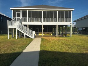 A two-story house with a covered porch, a staircase, and a concrete pathway leading to the entrance.