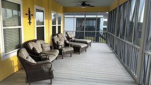 A covered porch with wicker furniture and a ceiling fan. - Angler Sunrise..Luxury House on water (Hackberry)