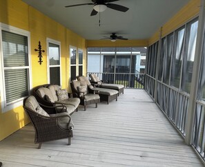 A covered porch with wicker furniture and a ceiling fan.