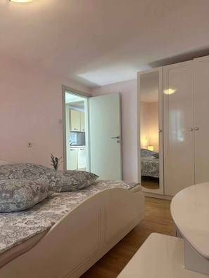 Una camera da letto con un letto, un comodino, un armadio e vista sulla cucina.