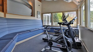 A gym with a blue bench, a spinning bike, and a treadmill. - Beautiful Fall Line Condo with Mountain Views on Shuttle Route B4A/B (Killington)