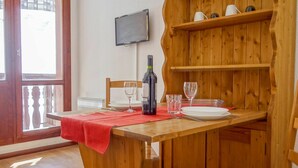 A wooden dining table with a red tablecloth, a bottle of wine, and two wine glasses. - Lovely apartment for 2 people with WIFI (Les Boisses)
