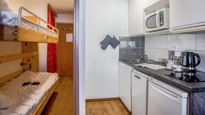 A compact room with a bunk bed, a small kitchenette with a microwave, a coffee maker, and a dishwasher. - Lovely apartment for 4 people with WIFI, TV, balcony and panoramic view (Les Boisses)