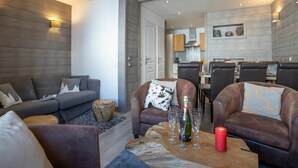 Una sala de estar moderna con un sofá, dos sillones, una mesa de centro y un comedor con sillas y una mesa.