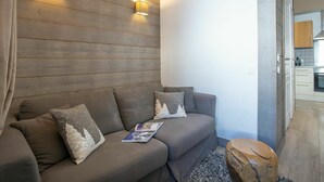 Una sala de estar moderna con un panel de pared de madera, un sofá gris con almohadones decorativos y una pequeña mesa auxiliar de madera.