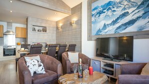 Una sala de estar moderna con sofás de cuero, una mesa de centro de madera y un televisor de pantalla plana grande.