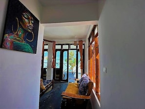 Ein Flur mit einer hölzernen Sitzbank, einem Bild an der Wand und Blick durch eine Glastür nach draußen.