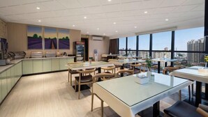 Un comedor moderno con mesas y sillas de vidrio, una barra de cocina y ventanas amplias con vistas a la ciudad.