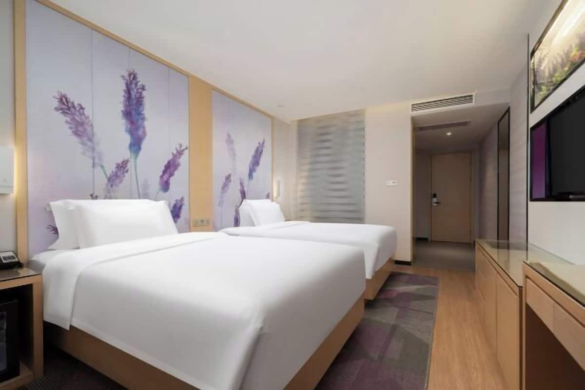 A hotel room with two beds, a TV, and a large window.