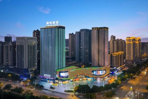 A high-rise building with a prominent sign at the top, surrounded by other tall buildings.