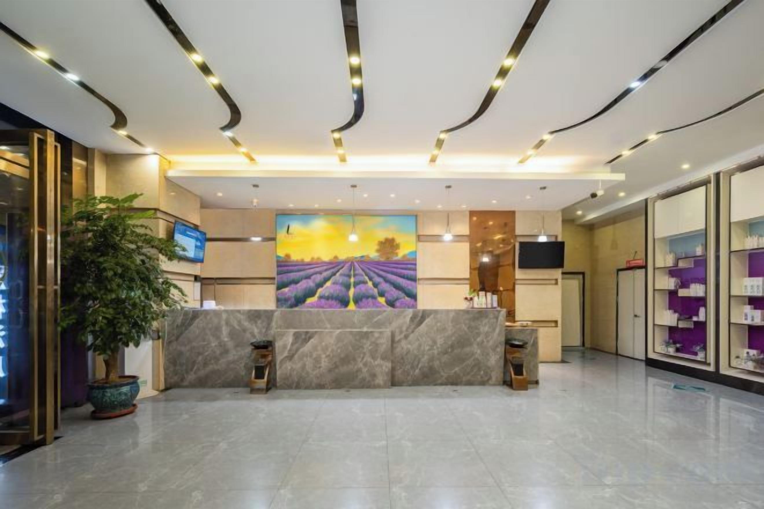 A hotel reception area with a marble reception desk, a large painting of a lavender field, and a potted plant.
