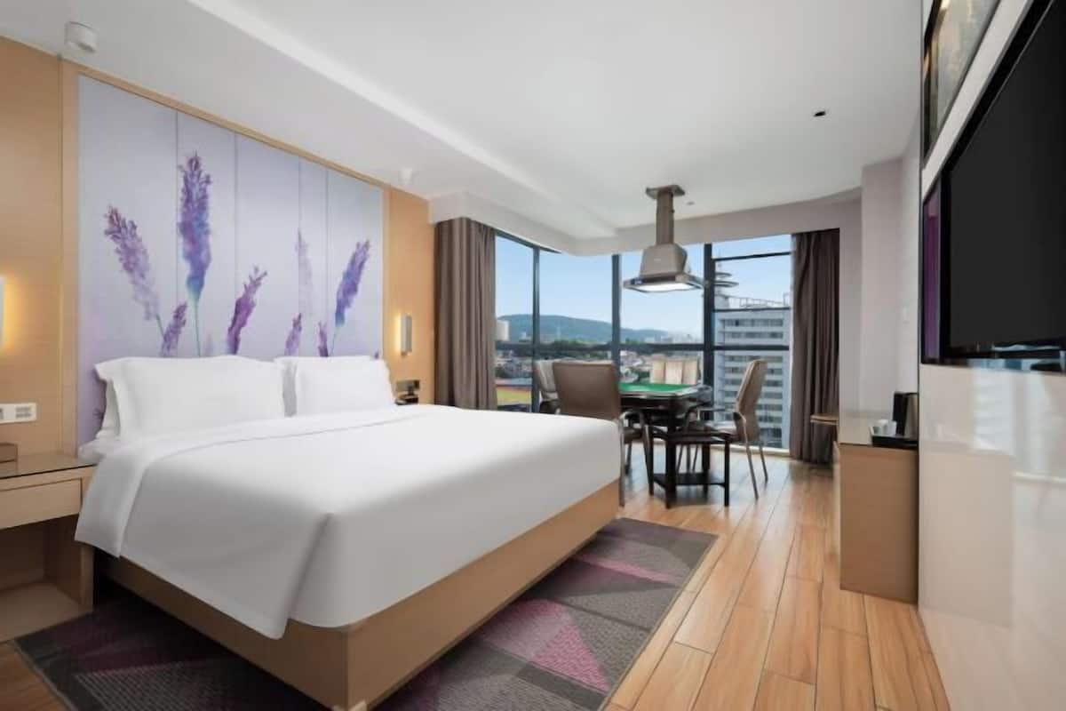A hotel room with a large bed, a desk, and a view of the city.