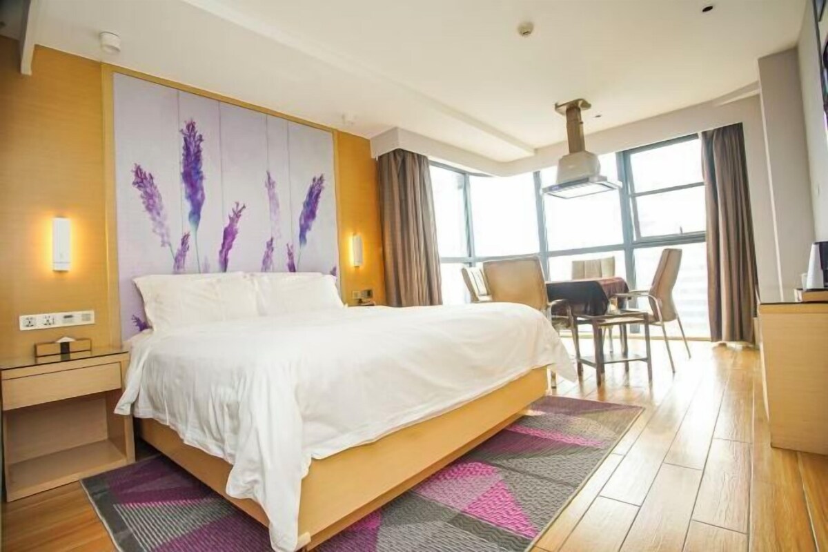 A modern hotel room with a large bed, a desk, and a chair.