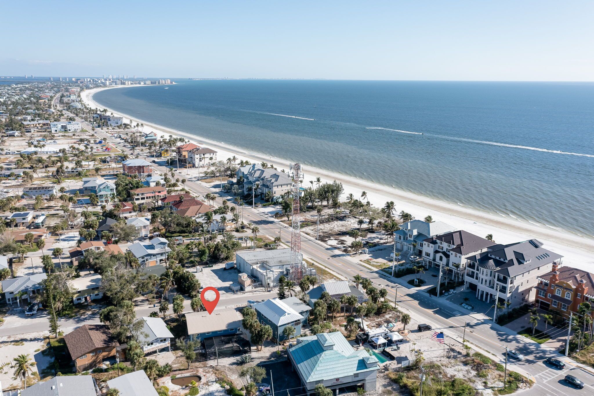 A coastal residential area with beachfront properties, roads, and a clear view of the ocean.