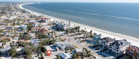 A coastal residential area with beachfront properties, roads, and a clear view of the ocean.