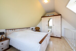A bedroom with a bed, a nightstand, a chair, a wardrobe, and a window. - Ferienwohnung Südstrand - Keine 5 Minuten vom Strand Entfernt (Wyk auf Föhr)