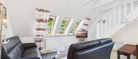 Un salon moderne avec un canapé, un téléviseur et un escalier.