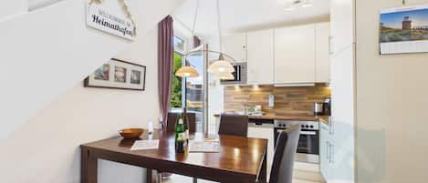 Een moderne keuken met witte kastjes, een houten aanrecht en roestvrijstalen apparatuur.