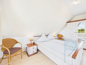 A bedroom with a bed, a nightstand, a chair, and a wardrobe.