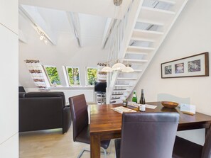 A modern dining area with a wooden table, leather chairs, and pendant lighting.