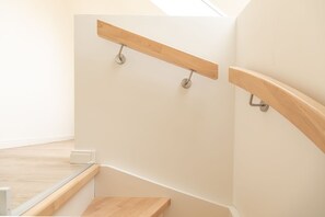 Eine moderne Treppe mit Holzhandläufen und Metallstreben, die zu einer oberen Etage führt.