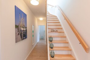 Eine Treppe mit Holzboden und Geländer, die zu einer Zwischenebene mit einer Tür führt.