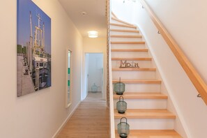 Ein Korridor mit Holzboden, einer Treppe mit der Beschriftung 'Moth' und einem Gemälde von Booten an der Wand.